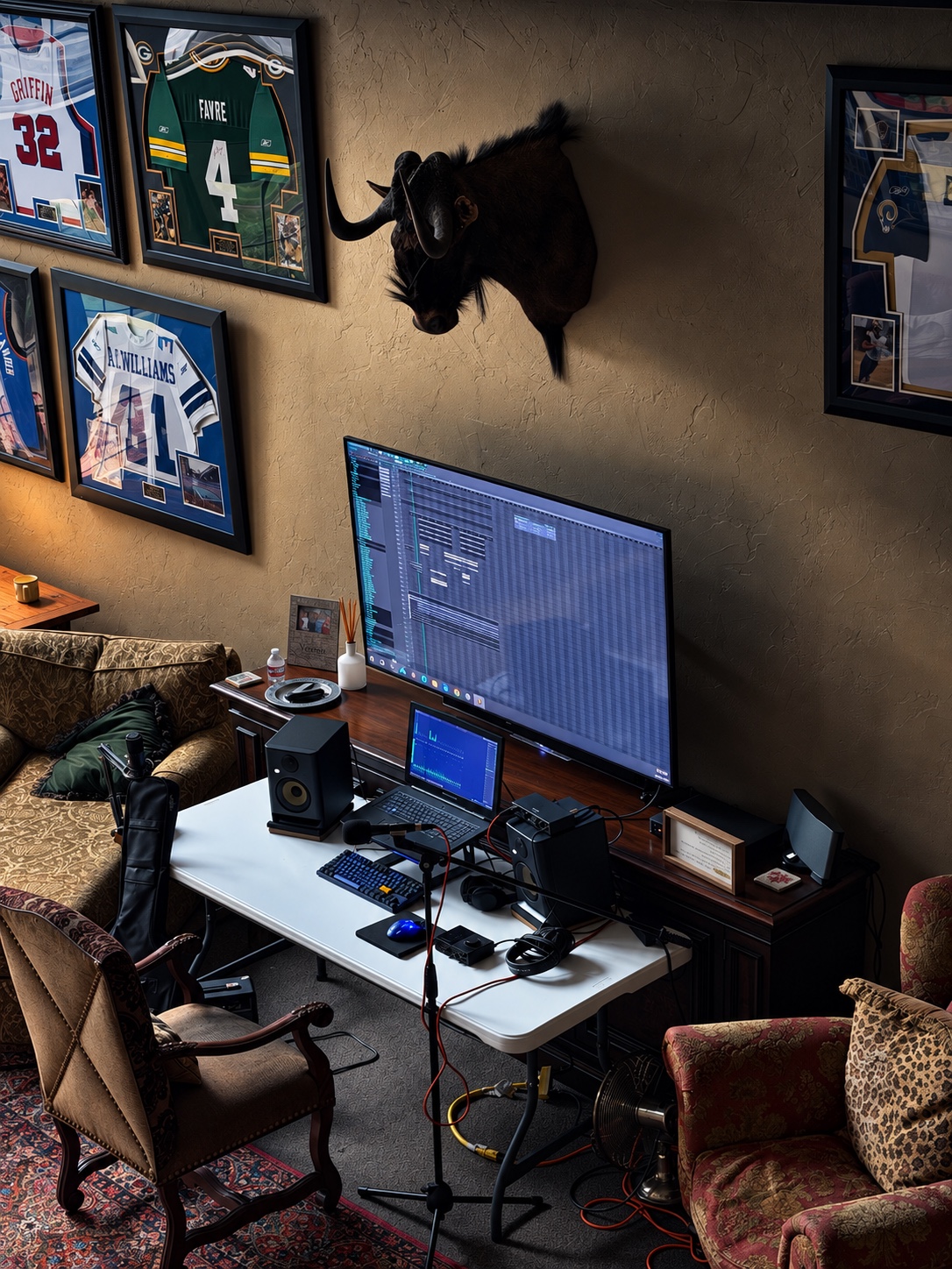 Wide view of the OUTONSPACE Studios workstation, recording equipment, and framed sports memorabilia