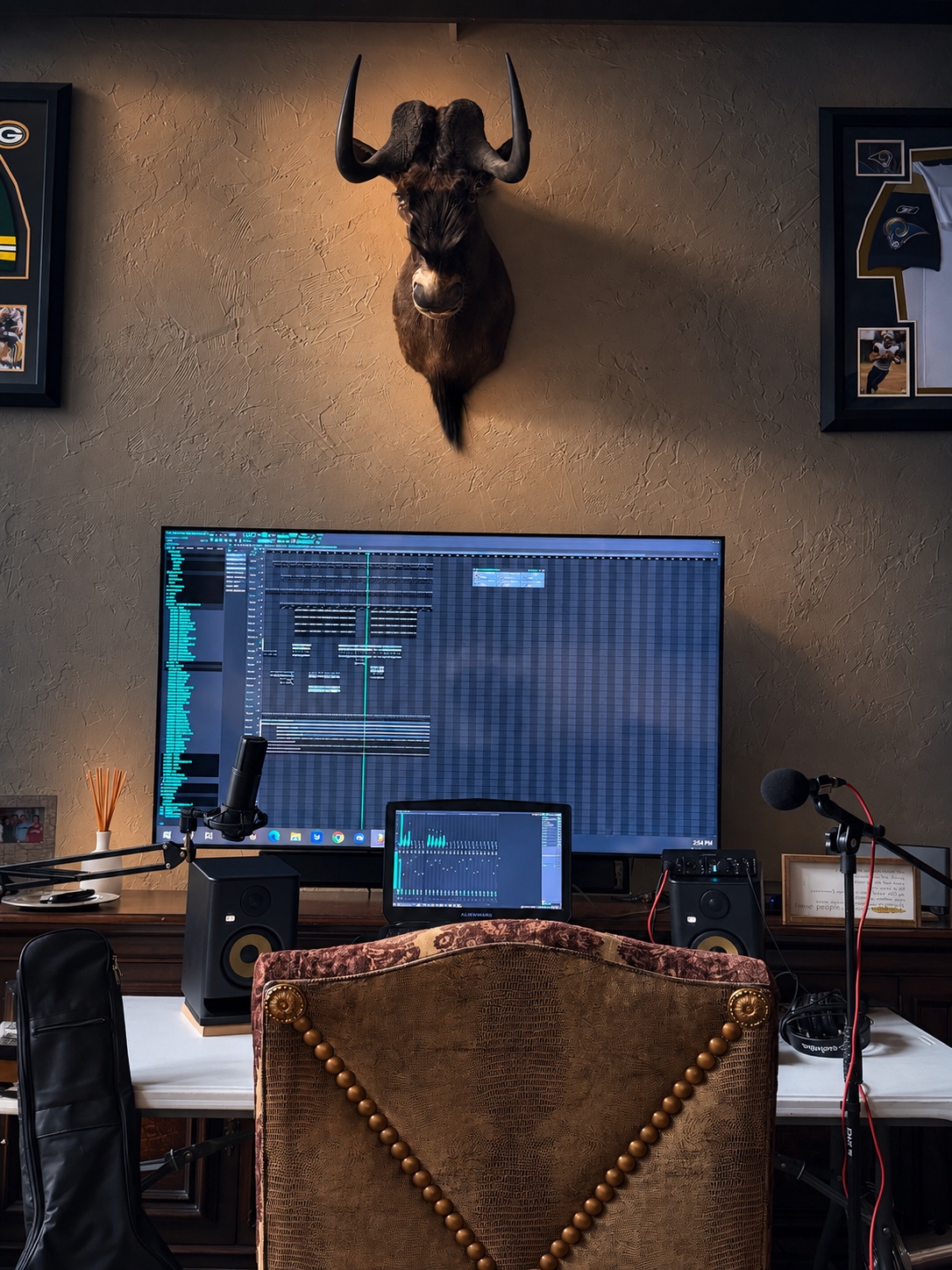 Front view of the OUTONSPACE Studios laptop workstation, large TV, monitors, and microphone